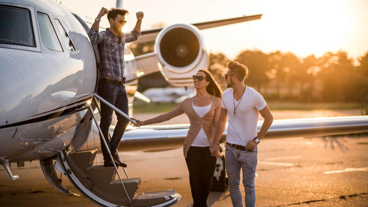 Young casual people with sunglasses standing in front of private jet airplane