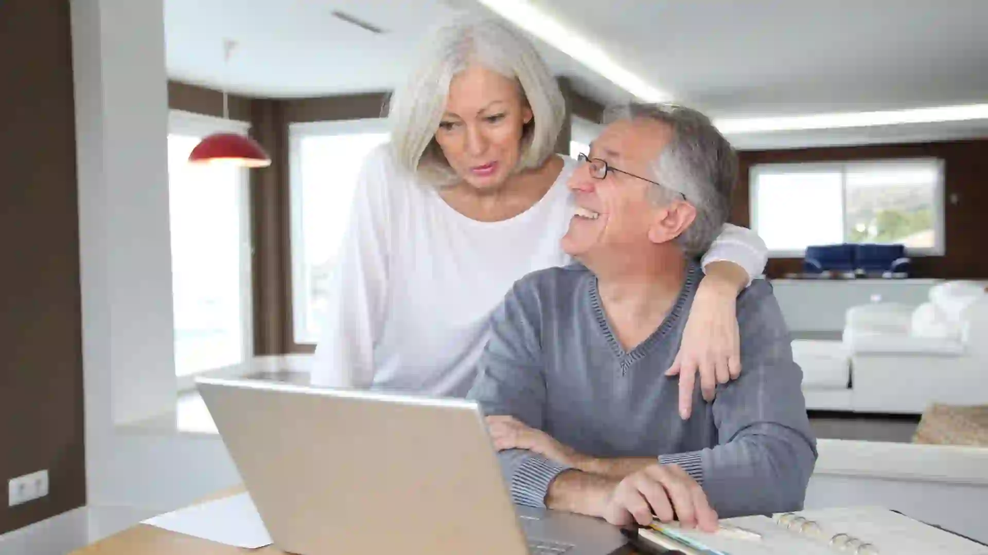 Senior couple using laptop and celebrating a win with their finances, retirement planning, Social Security and more.