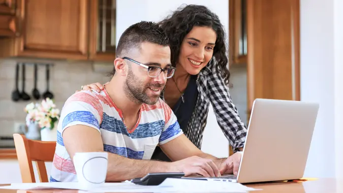 Young woman sitting at home and making home finances, using laptop.