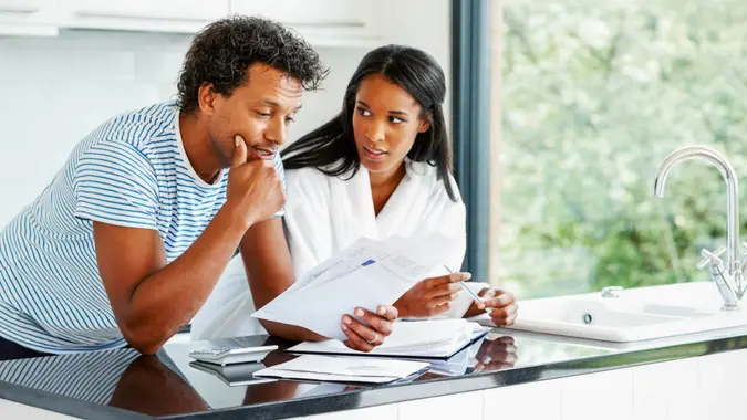 Portrait of worried young couple reading financial documents in kitchen, fees, America, money, payment, avoid fees, bills, debt