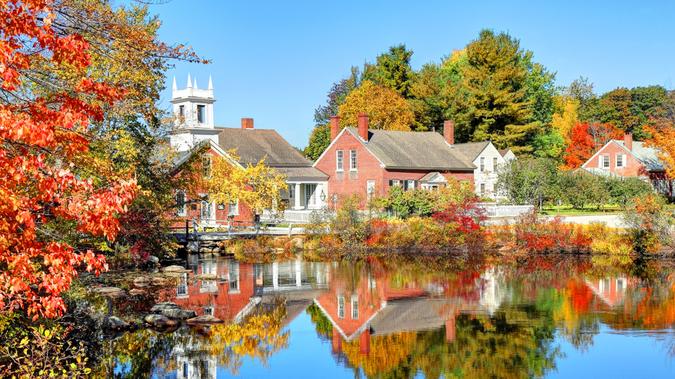 The quaint village of Harrisville New Hampshire reflecting on a small pond in autumn.