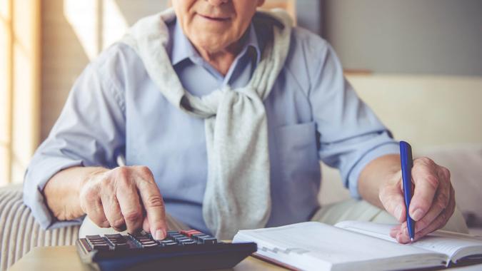Senior man making calculations with calculator