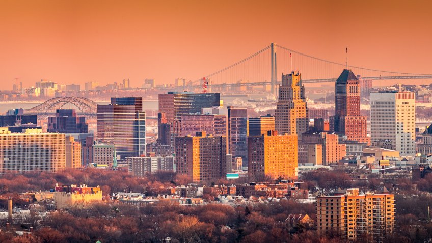 Newark New Jersey skyline viewed from Eagle Rock reservation under an orange sunset.