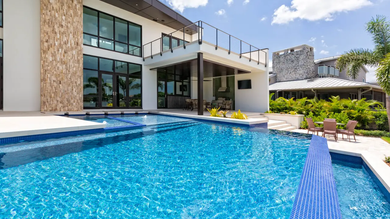 A beautiful modern swimming pool and home on a sunny day with outdoor living area