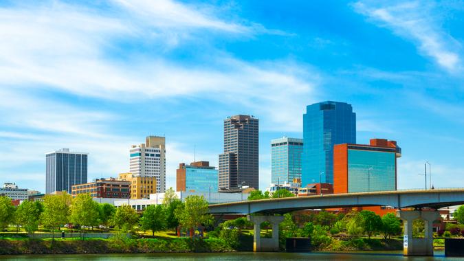 Little Rock downtown skyline with the Arkansas river in the foreground and soft wispy clouds in the background.