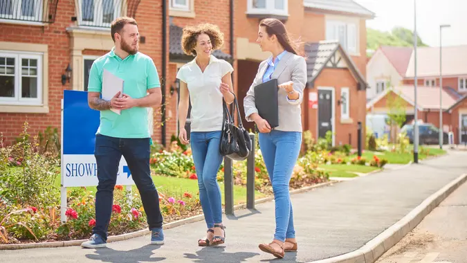 HOA, fees, America, money, payment, avoid fees, bills, debt, a mid adult couple browse a new housing development whilst listening to the sales assistant or estate agent .
