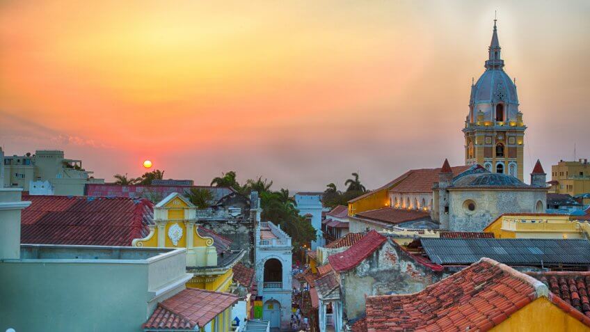 View over the rooftops of the old city of Cartagena during a vibrant sunset.