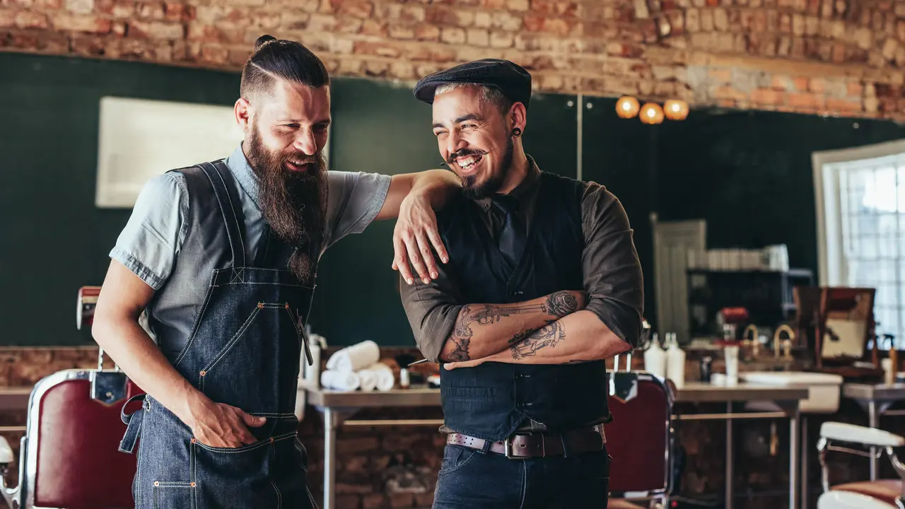 Shot of hairdresser with a man standing at barbershop.