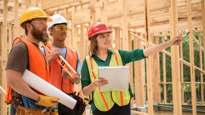 engineer, foreperson, or quality control inspector discusses blueprint plans with workers