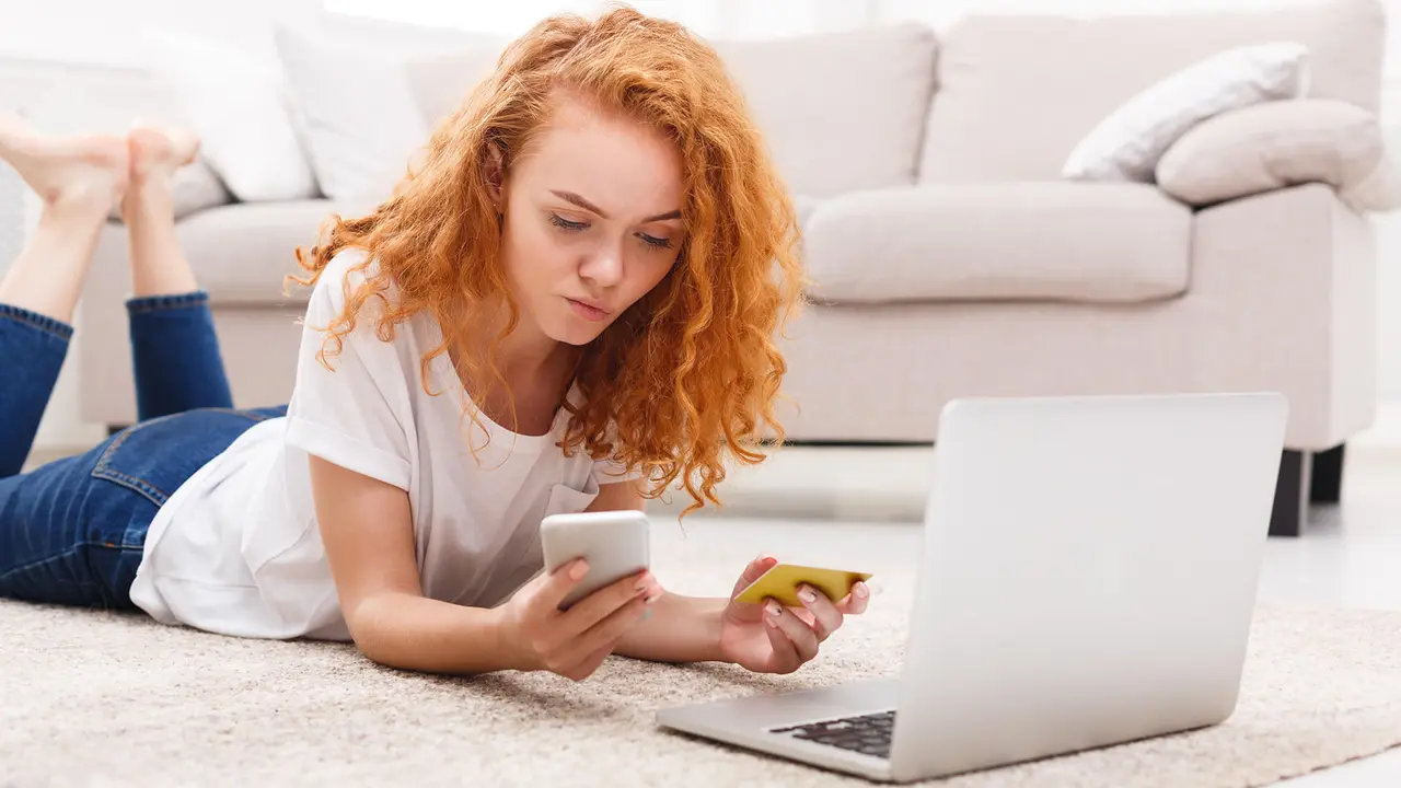 woman lying on floor looking at credit card