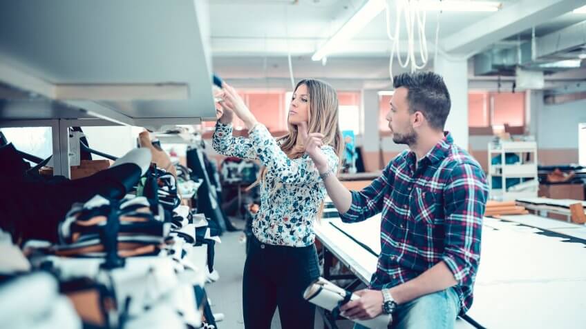 Man and Women Selecting Fabric From Storage Shelves.