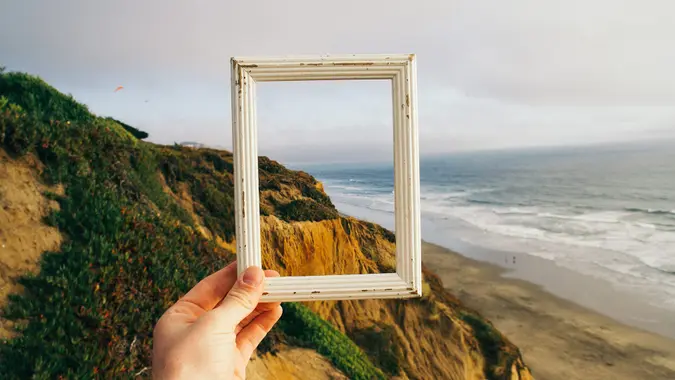 hand holding frame with ocean behind it.