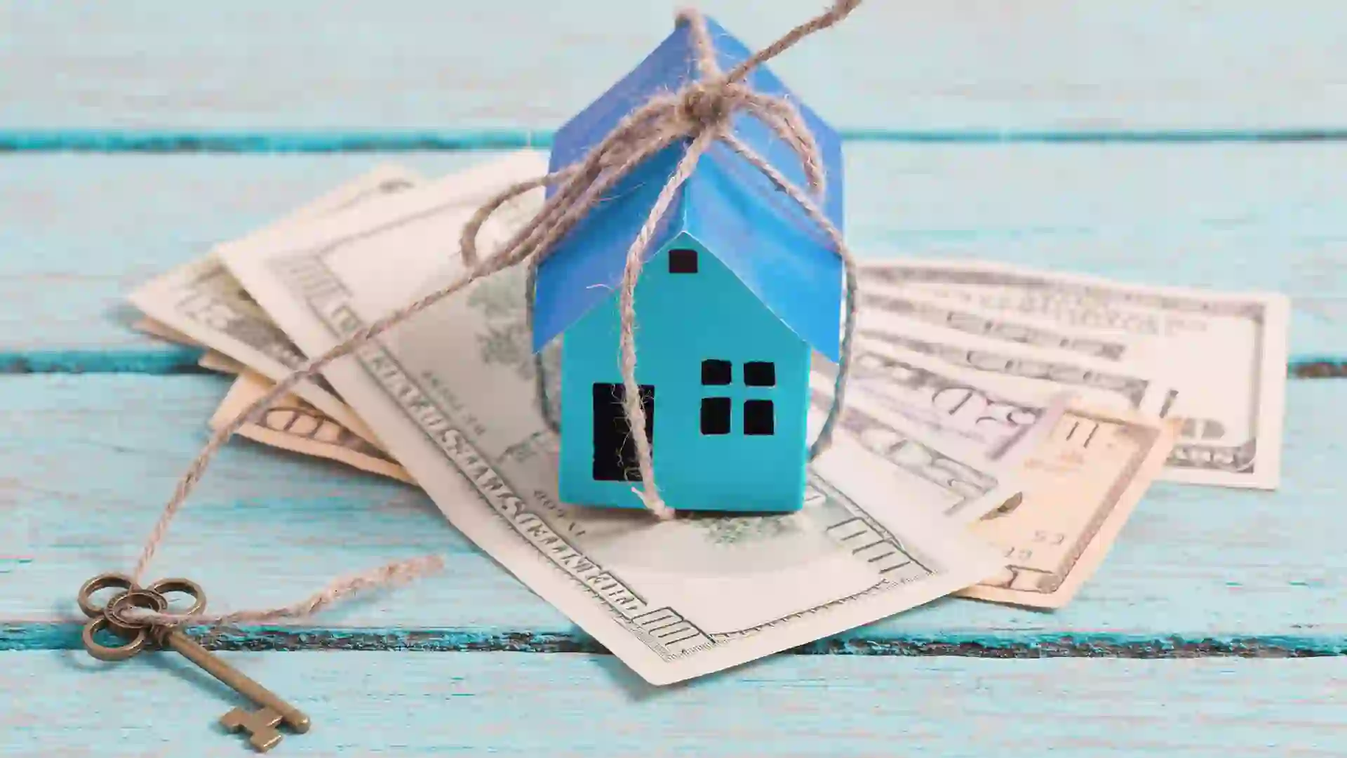 House from the paper and money on wooden background.