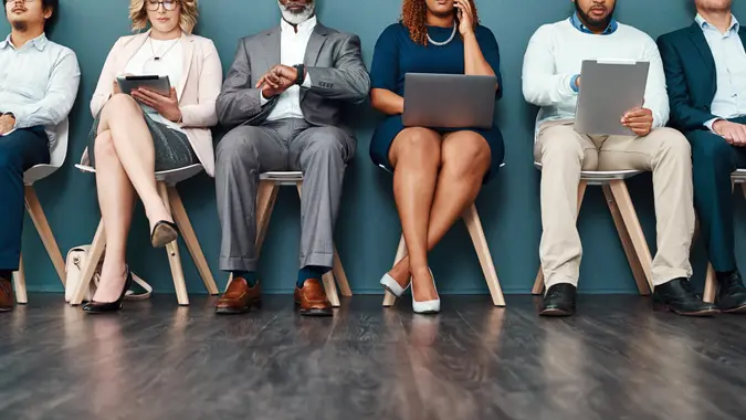 Cropped studio shot of a group of a diverse group of businesspeople using wireless devices while waiting in line.
