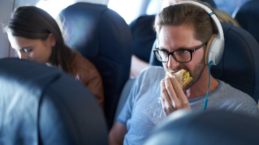 Man eating sandwich in economy class in airplane.