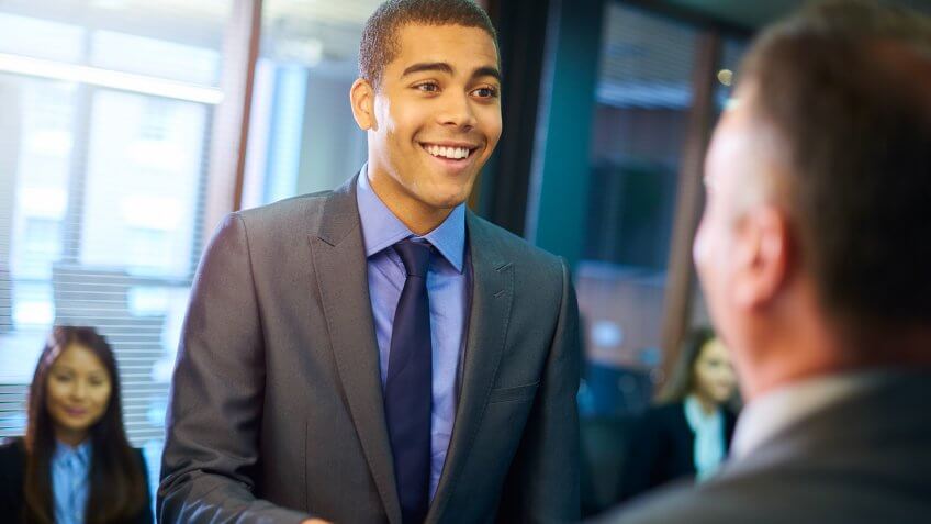 young man steps forward as he is called in for his interview and shakes hands with his possible new employer. young man steps forward as he is called in for his interview and shakes hands with his possible new employer.