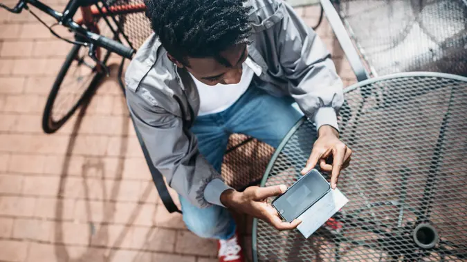 A young African American man in New York City deposits his paycheck to his bank using his smart phone to photograph the check.