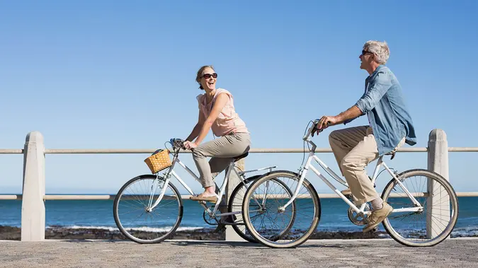 Happy casual couple going for a bike ride on the pier on a sunny day.