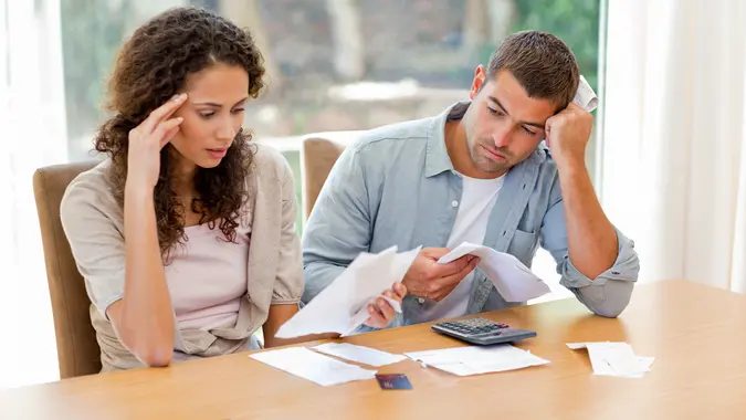 Young couple calculating domestic bills at home.