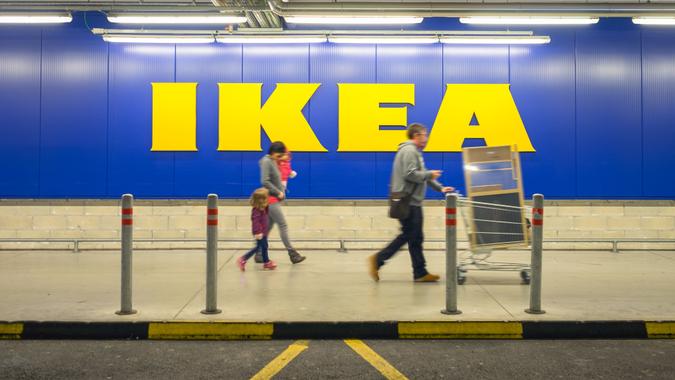 Chieti, Italy - November 19, 2016: A family walking in the car parking after shopping at Ikea store; the big sign of the store is in the background.