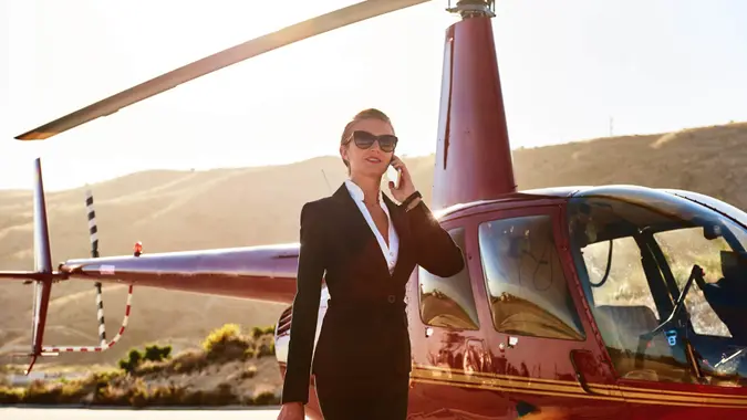 Elegant business woman talking by phone near the helicopter.