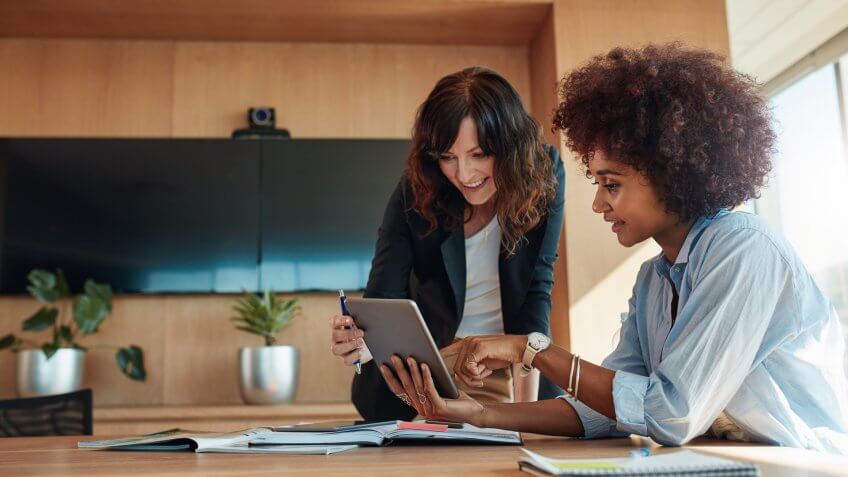 businesswoman showing something on digital tablet to her female colleague