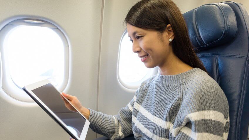 young woman streaming on ipad in airplane