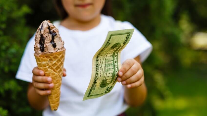 Little girl exchanging ice cream for dollar.