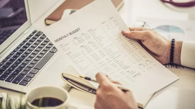 Hands holding a monthly budget sheet at a desk