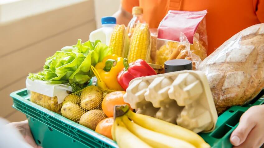Person holding a bin of groceries for delivery