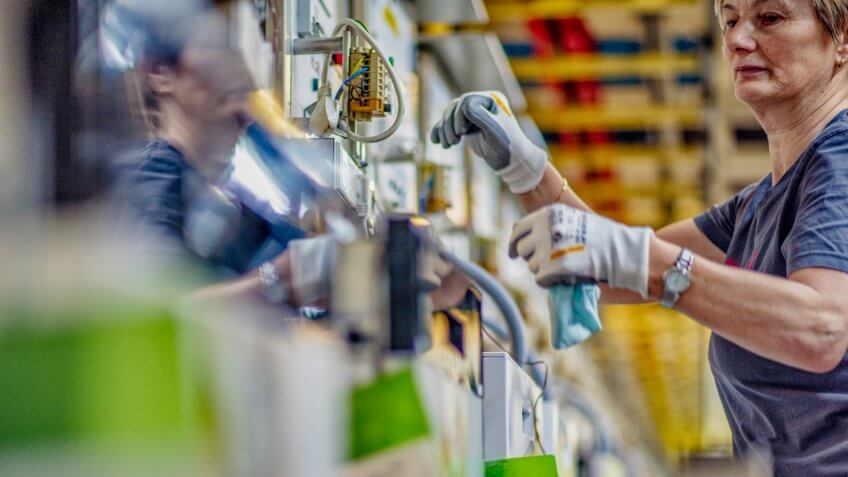 Low angle shot of a female worker in an appliance factory assembling and appliance.