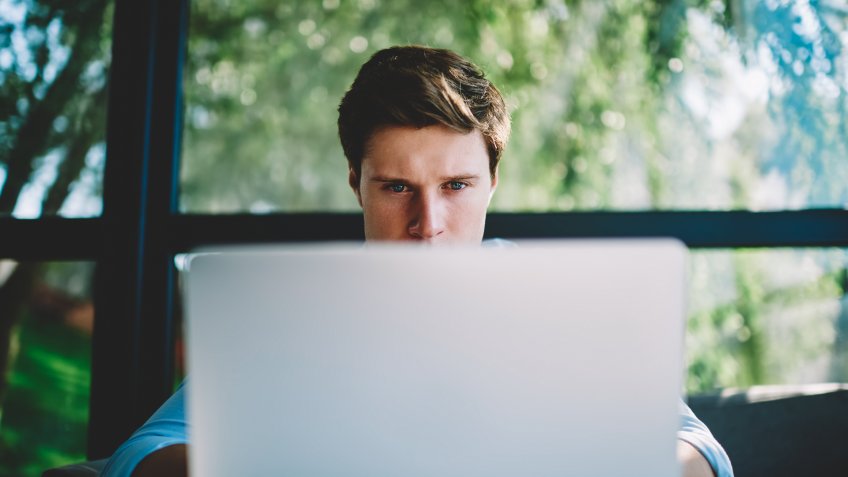 Man behind laptop focused on viewing the screen