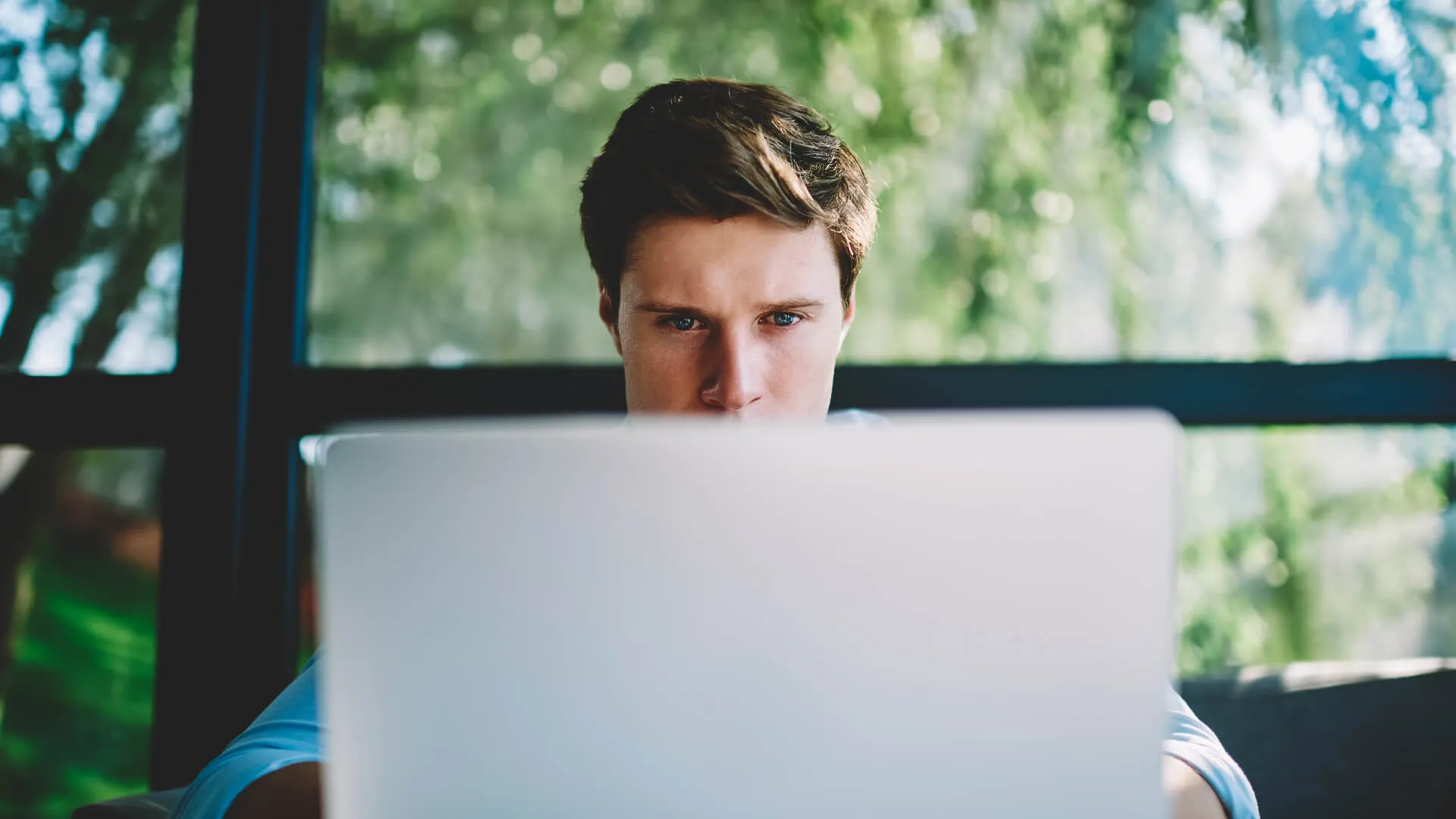 Man behind laptop focused on viewing the screen