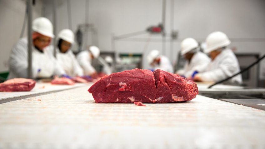 Workers processing meat for packaging