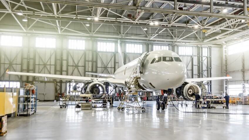 Passenger aircraft on maintenance of engine and fuselage repair in airport hangar.