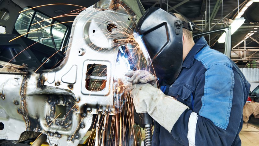 Automotive Industry worker welding vehicle metal