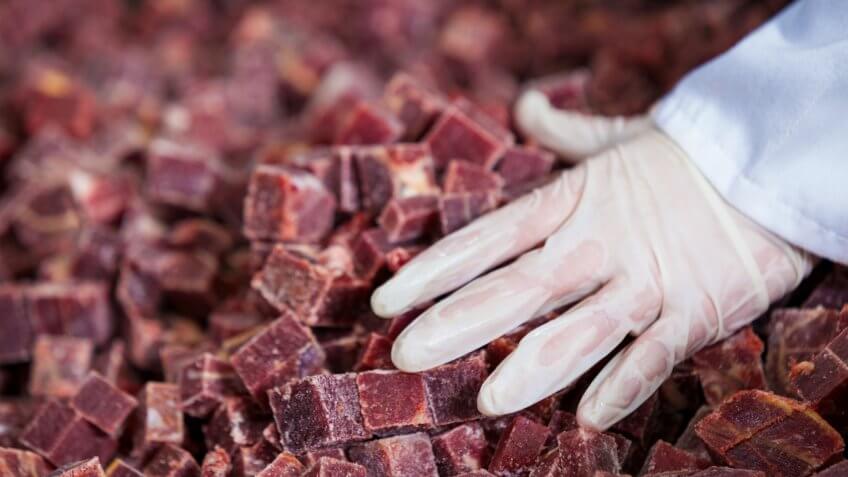 Worker handling cubed meat