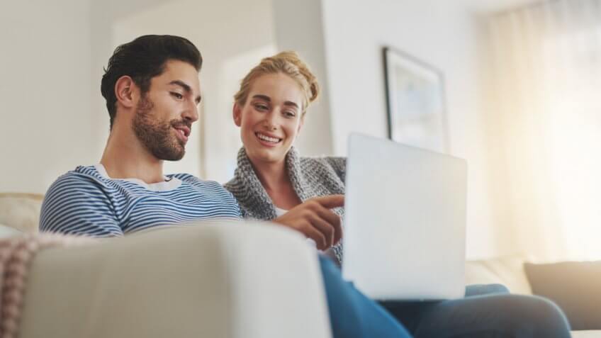 Shot of a young couple using a laptop on their sofa at home.