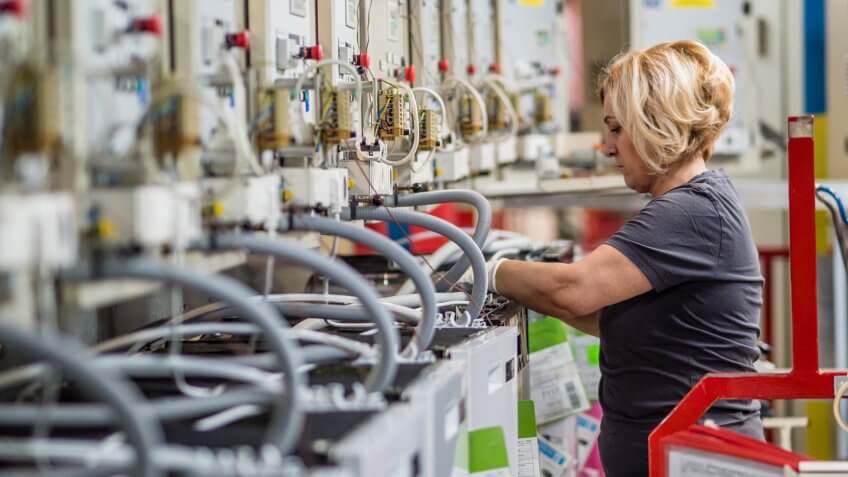 Female factory worker working on production line in appliance manufacturing factory.