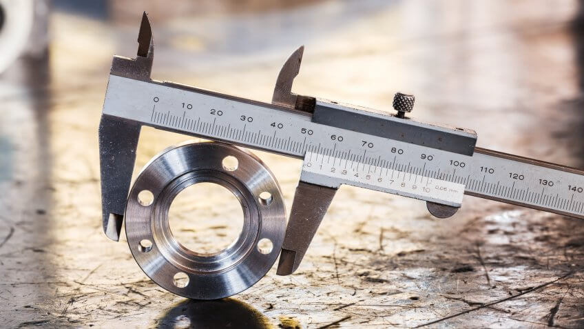 Close up vernier caliper measure diameter of stainless steel flange.