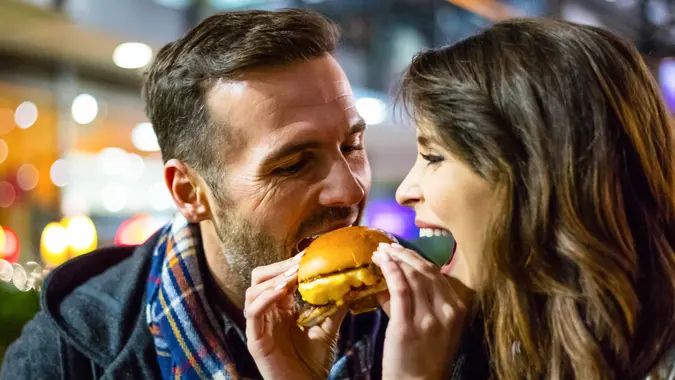 Couple enjoying fast food outdoors in city.