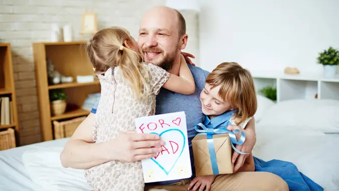 Little daughters embracing their father to congratulate with fathers day.