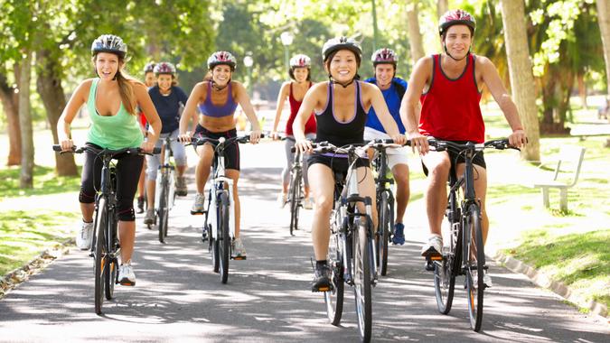 Group Of Cyclists On Cycle Ride Through Park Group Of Cyclists On Cycle Ride Through Park During Summer.