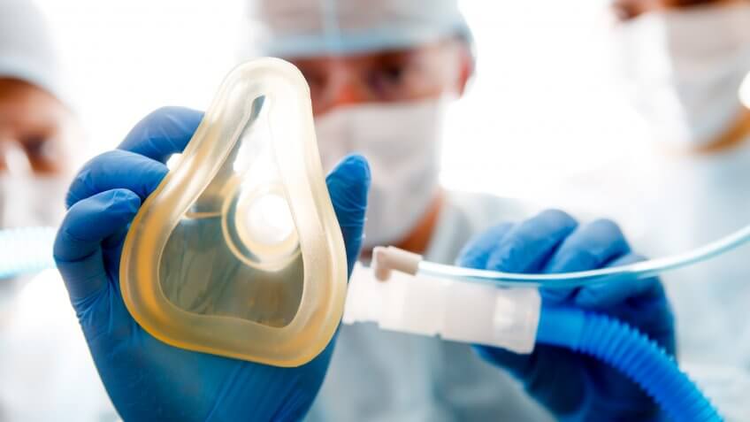 Anesthesiologist placing oxygen mask on patient, first-person view