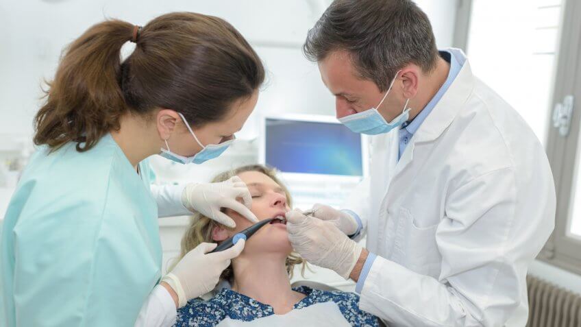 Oral surgeon and assistant operating on a patient's teeth