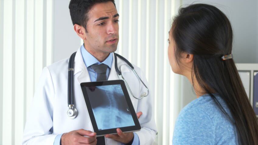 Physician displaying an x-ray of a neck and spine to a patient