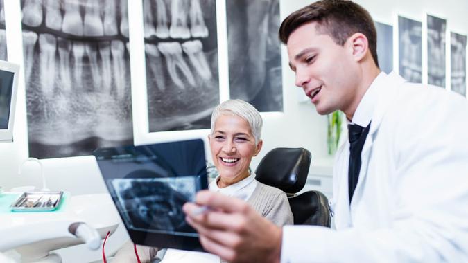 Dentist checking x-ray image or scan while beautiful senior woman receiving a dental treatment.