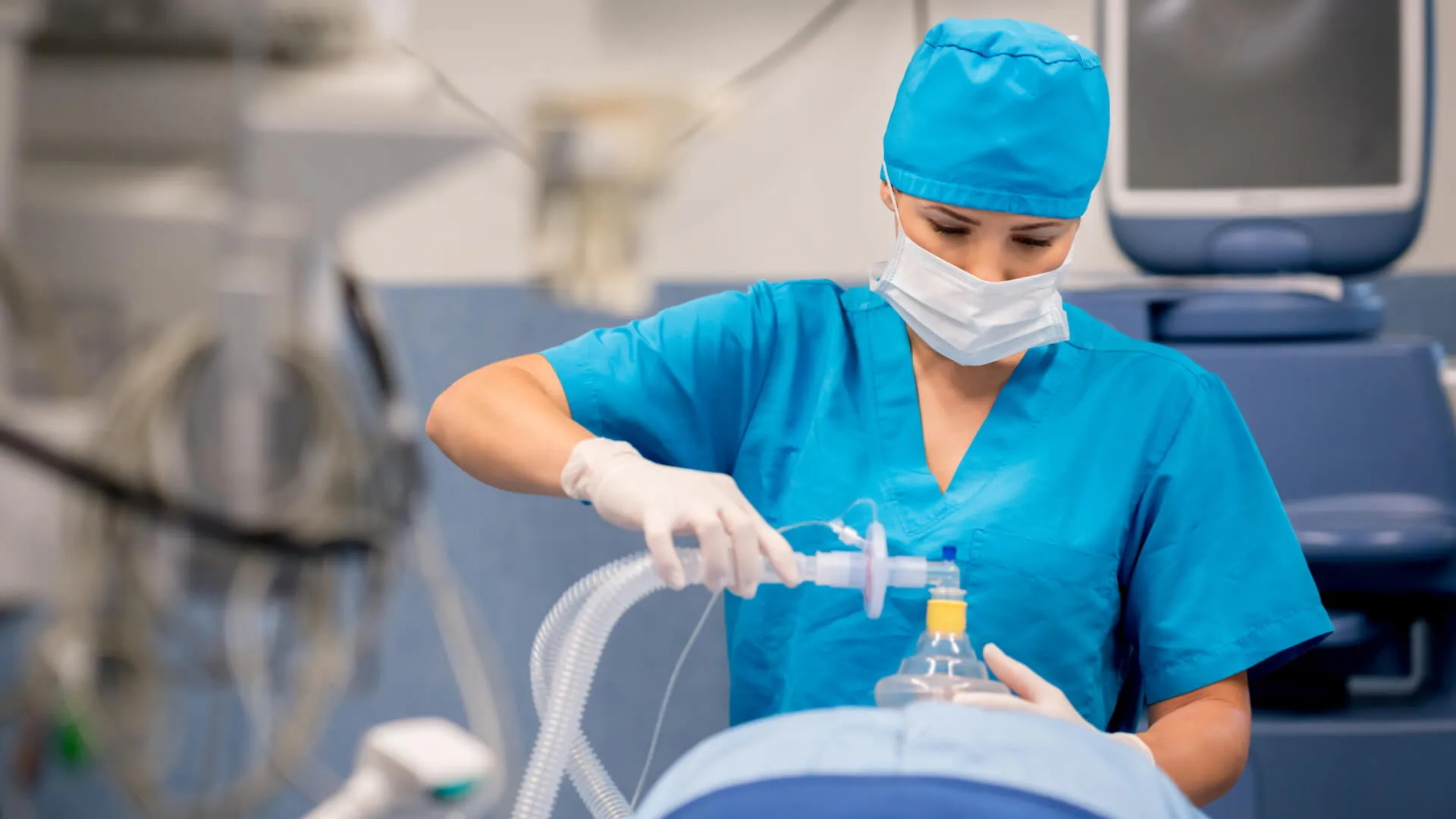 Nurse anesthetist putting oxygen mask to patient during surgery