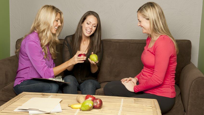 Nutritionist and dietetic technician explaining the benefits of fruits to a patient