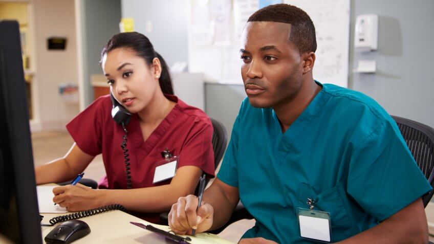 Health technologists or technicians examining medical technology on computer monitors